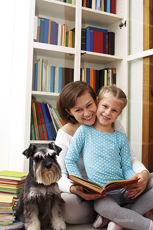 Mom reading to daughter with family dog