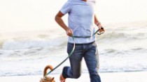 Man running on the beach with his dog